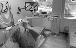 A dental examination room with a dental chair, equipment, and a wall-mounted monitor.